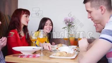 一群男女朋友坐在桌子旁的咖啡馆里享受着他们的饭菜